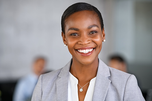 Portrait of mature beautiful black businesswoman looking at camera. Successful african american woman standing in office with satisfaction. Confident and proud woman entrepreneur smiling with copy space at conference room.