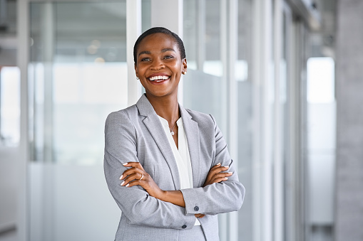 Happy smiling confident middle aged Asian older senior female leader businesswoman standing in modern office workplace looking at camera arms crossed. Business successful executive concept. Portrait.