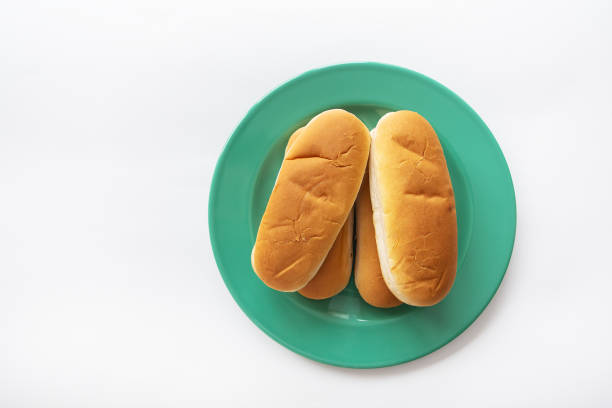 Fresh hot dog buns which lie on a green plate. View from above