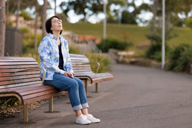 Japanese woman sitting on a park bench, thinking.