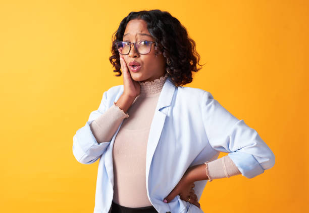 istock Doubtful, surprised and shocked boss posing with trendy style in isolated background, copy space. Puzzled woman wearing glasses pouting. Portrait of lady feeling jaw ache, pain and discomfort 1413769591