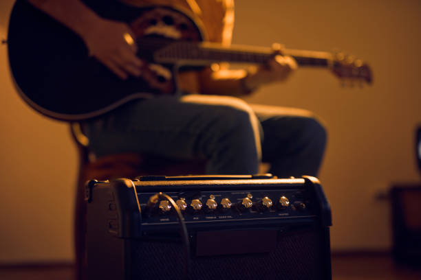 male musician playing acoustic guitar on the amplifier in retro vintage room. - fingerstyle imagens e fotografias de stock