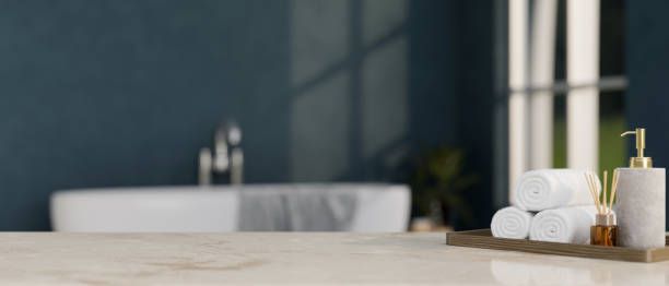 istock Modern marble bathroom tabletop with copy space over modern bathroom with bathtub in background. 1413771111