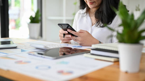 istock Asian businesswoman at her office desk using her smartphone. cropped image 1413772233