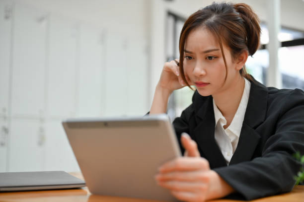 istock Concentrated young Asian businesswoman using digital tablet, working in the office. 1413772488