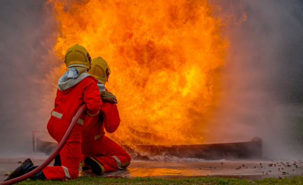 istock Two brave firefighter using extinguisher and water from hose for fire fighting, Firefighter spraying high pressure water to fire, Firefighter training with dangerous flames, Copy space-Image 1413773181