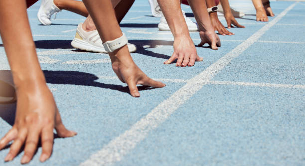 gros plan d’un groupe déterminé d’athlètes en position de départ pour commencer le sprint ou la course sur piste sportive. mains de divers sportifs prêts à participer à l’épreuve olympique d’athlétisme - sporting position vitality blurred motion strength photos et images de collection