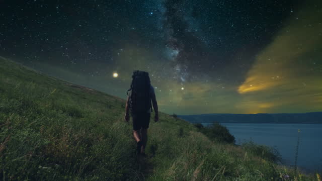 The man trekking along the mountain coast on starry sky background. slow motion