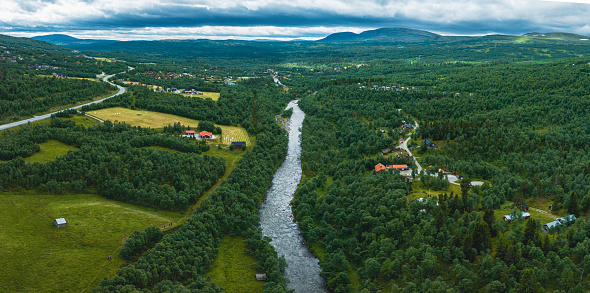 A raging river runs through deep green forest landscape. Seen from above in the village of Bruksvallarna, Harjedalen, Sweden.