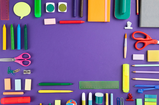 Directly above view of a large group of school supplies on purple background