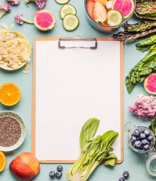 Healthy smoothie ingredients around  clipboard with blank paper sheet on light table, top view, frame. stock photo