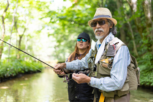 Senior man teaching younger woman how to do Fly Fishing