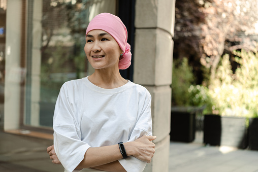 Portrait of an Asian female cancer patient with a headscarf relaxing outdoors