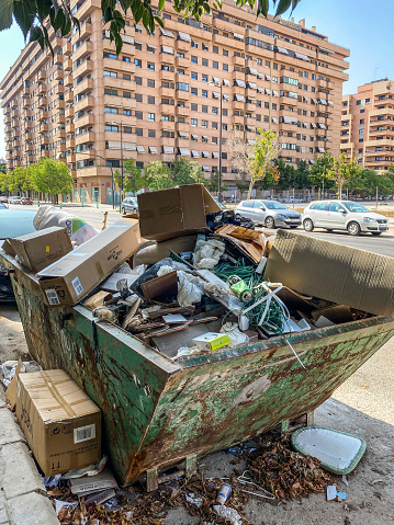 Valencia, Spain - July 24, 2022: Close-up view of huge container full of garbage in the street. These are often used in building remodeling where a lot of rubble is generated and is needed to be removed. Once full the contents of the container are disposed in a proper place