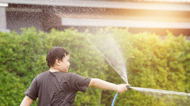 istock Young boy water hose at lawn 1413789108