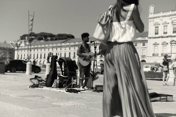 Lisbon, Portugal - July 2, 2022: A street musician plays guitar and sings at the Praça do Comércio square in Lisbon downtown.