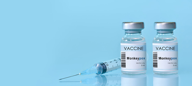 Two vials with vaccine Monkeypox with a syringe on a blue background.The concept of medicine, healthcare. Monkeypox is a viral zoonotic disease. Monkeys may harbor the virus and infect people.