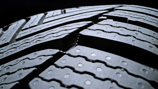 Extreme close-up of vehicle tyre against black background.