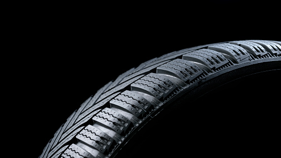 Close-up of vehicle tyre against black background.