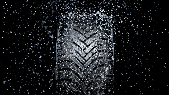 Close-up of ice splashing on vehicle tyre against black background.