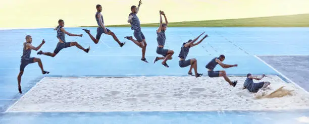 Photo of A sequence of a fit male athlete jumping in a sandpit competing in the long jump. Professional athlete or track racer during long or triple jump attempt is a competitive sports event or training