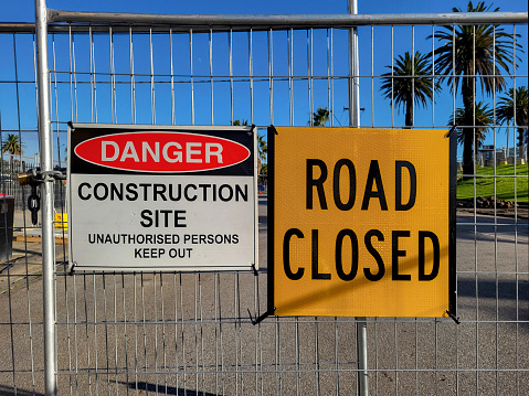 Construction site warning signs in yellow informing of road closure. Danger Construction Site sign with unauthorised persons instructed to keep out.
