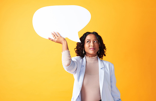 Worried, Pensive and thinking woman pondering a question or difficult decision. African American female brainstorming ideas, holding an empty speech bubble against yellow copyspace background.