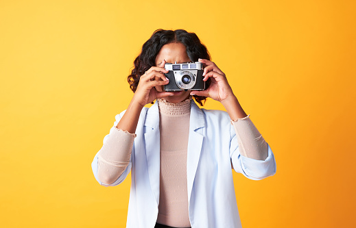 Fun, creative and confident photographer taking picture on digital camera for social media, blog or photography website. Ambitious and artistic artist capturing photos on yellow copy space background