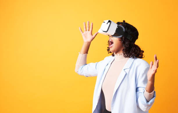 istock Excited, shocked and amazed woman using a virtual reality headset and saying wow for 3D ai world. Female using VR glasses to play games and interacting with metaverse against yellow studio background 1413796922