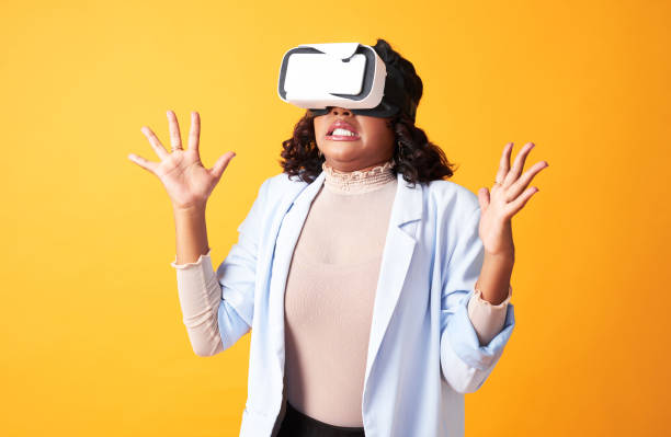 istock Watching metaverse, virtual reality and cyber world through vr goggles and looking surprised, shocked and amazed. Anxious woman wearing 3D headset on yellow copy space background, playing scary game 1413796970