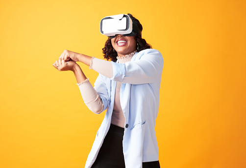 Playing game on metaverse vr headset, enjoying and having fun in virtual reality, cyber and 3D world. Excited, happy and playful woman using hand gesture to swing or on yellow copy space background