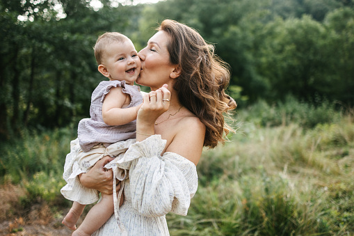 Mother kissing her baby in the nature