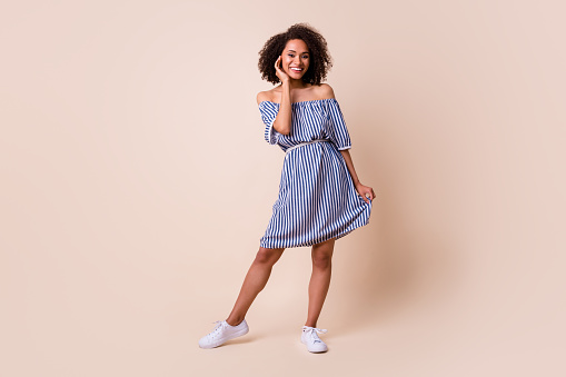 Full length photo of pretty sweet lady wear striped outfit smiling walking isolated beige color background.