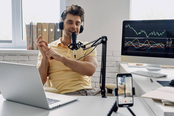 istock Young man in headphones using microphone and gesturing while recording his business podcast 1413800067
