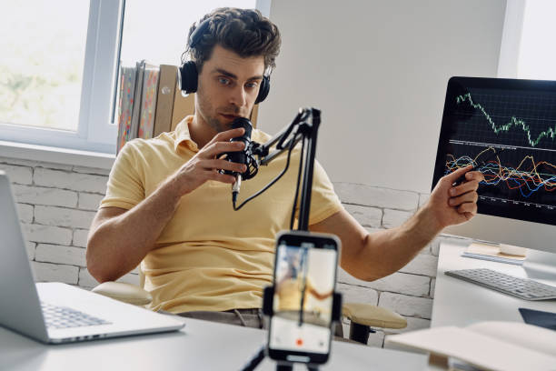 istock Confident man in headphones using microphone and gesturing while recording his business podcast 1413800068