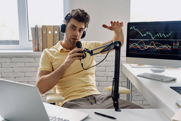istock Confident man in headphones using microphone and gesturing while recording his business podcast 1413800424
