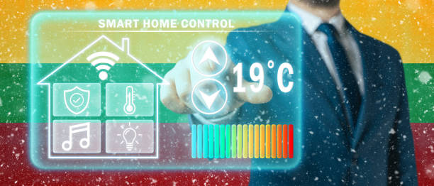 istock Frozen citizen of Lithuania adjusting heating temperature on a virtual screen of smart home controller, winter blizzard background. Concept of forced thrift because increased price for heating home 1413800551