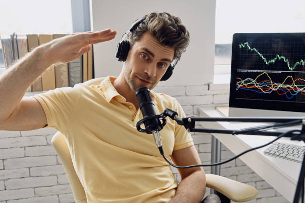 Handsome man in headphones using microphone and gesturing while recording his business podcast stock photo