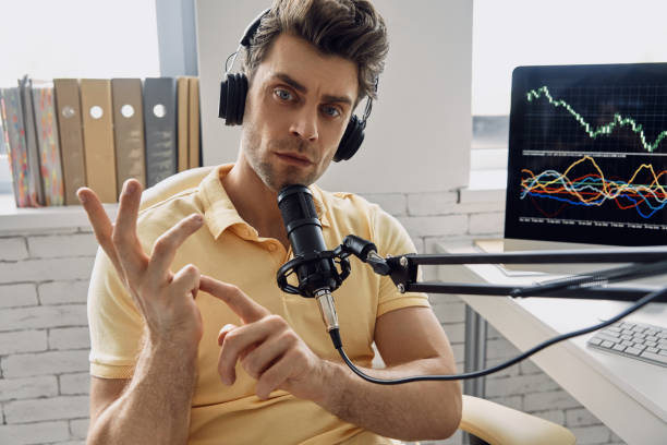 istock Confident man in headphones using microphone and gesturing while recording his business podcast 1413800647