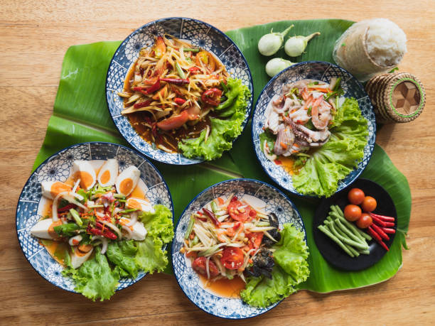 ensalada de papaya, ensalada de mariscos, ensalada de huevo salado con arroz pegajoso al vapor y verduras en hojas de plátano - thai cuisine fotografías e imágenes de stock