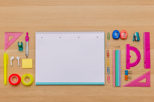 Back to school concept, creative layout with various school supplies, pencils, ruler, tapes, notebook, paper clips, pencil sharpener, notepads, markers on wooden background with copy space