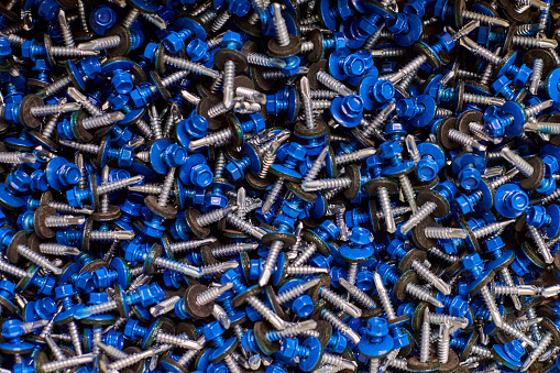 Bunch of galvanized self-drilling screws with washer and blue hexagonal head, hardware background