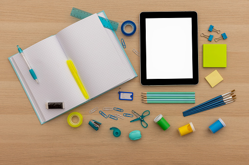 Back to school concept, creative layout with various school supplies, pencils, ruler, tapes, notebook, paper clips, pencil sharpener, notepads, markers and tablet on wooden background with copy space
