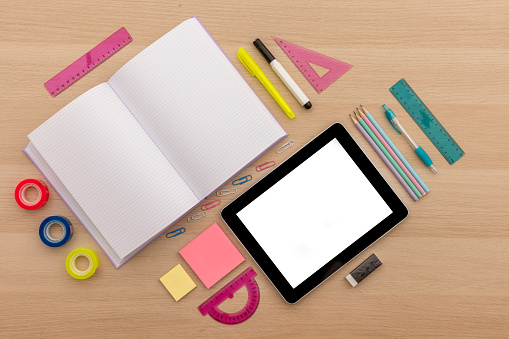 Back to school concept, creative layout with various school supplies, pencils, ruler, tapes, notebook, paper clips, pencil sharpener, notepads, markers and tablet on wooden background with copy space