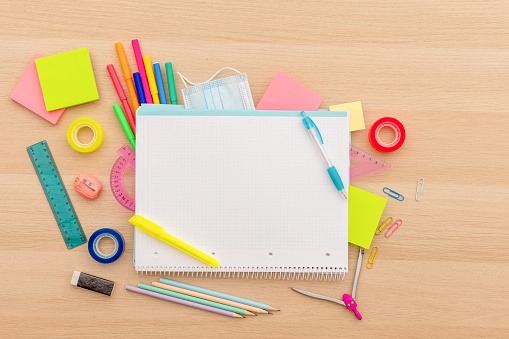 Back to school concept, creative layout with various school supplies, pencils, ruler, tapes, notebook, paper clips, pencil sharpener, notepads, markers on wooden background with copy space