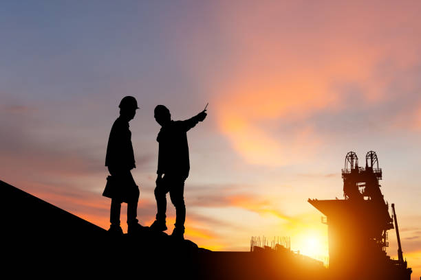 istock Silhouette of Engineer and worker man checking project at building site background, Infrastructure construction site at sunset in evening time 1413803470