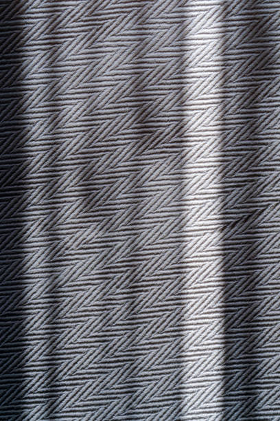 eine nahaufnahme der grauen tagesdecke von oben. die sonnenstrahlen beleuchten die textur und das gewebe des stoffes. zickzack- oder chevron-muster. - chevron textile striped close up stock-fotos und bilder