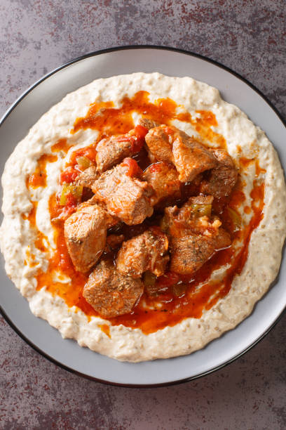 Hunkar Begendi Meat Stew over Eggplant Sauce closeup in the plate. Vertical top view Hunkar Begendi Meat Stew over Eggplant Sauce closeup in the plate on the table. Vertical top view from above hunkar begendi stock pictures, royalty-free photos & images