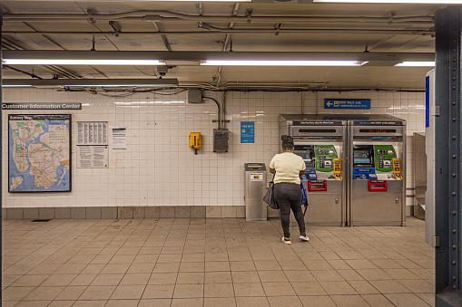 New York Subway, Manhattan, New York, NY, USA - June 30, 2022: Woman buying a ticket at a automate at 86th Street station in central Manhattan