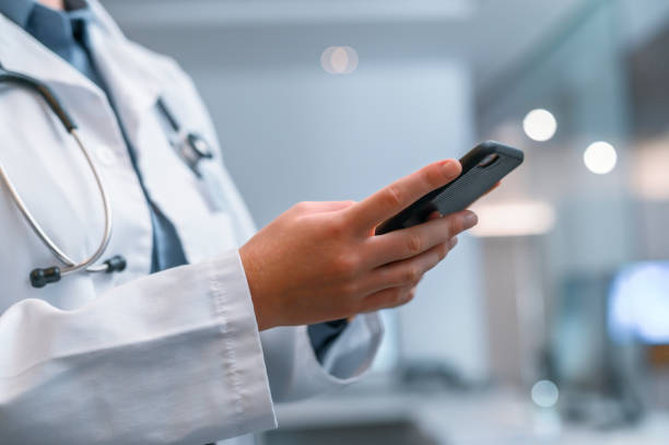 istock Closeup of a doctor reading a phone, browsing social media while taking a break from working in a hospital. Health care professional texting while checking the internet or responding to an email 1413809208